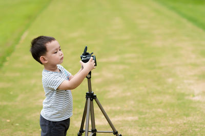 Cute boy photographing while standing at park