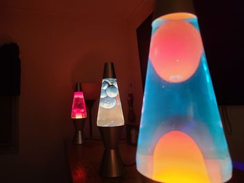 Close-up of illuminated electric lamp on table against wall