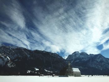 Scenic view of snow covered mountains against cloudy sky