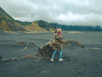 Rear view of woman on beach against sky