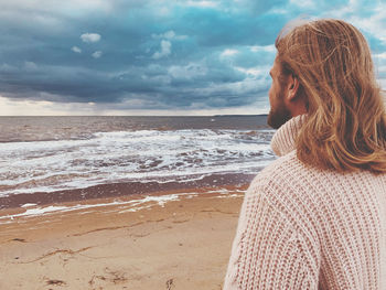 Rear view of bearded young man looking at sea against sky