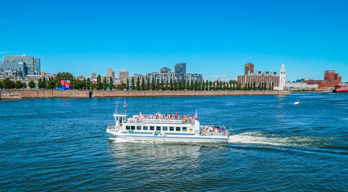 Boat sailing in river against clear blue sky