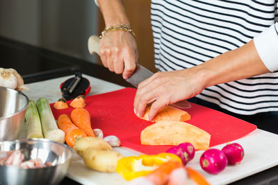 Woman slicing vegetables while cooking stew. close up of woman hands cutting vegetables