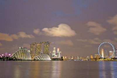 Illuminated cityscape by sea at night