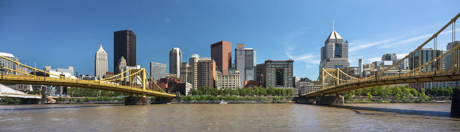 Bridge over river amidst buildings in city against sky