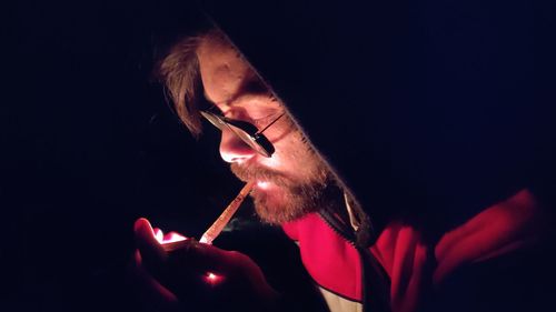 Midsection of man smoking cigarette against black background