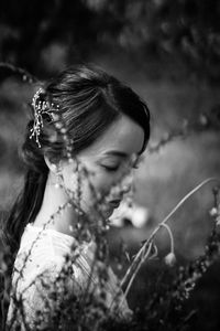 Side view of mid adult woman looking down while standing by plants