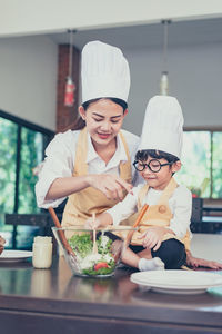 Full length of woman holding food in kitchen