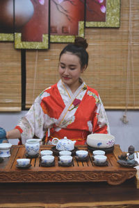 Young woman wearing kimono with tea on table sitting at home