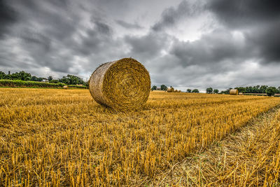 Hay bales on field against sky