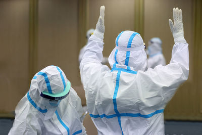 Doctors with arms raised wearing protective workwear