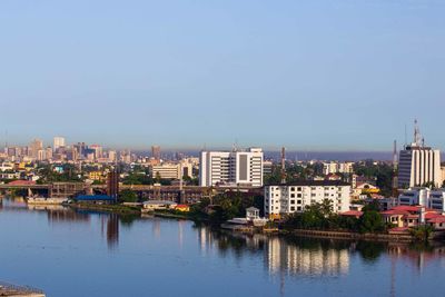 View of cityscape by river against sky