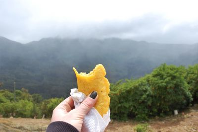 Close-up of woman holding food cone against mountain