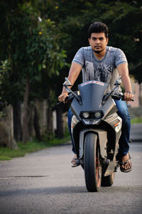 Portrait of young man riding motorcycle on road