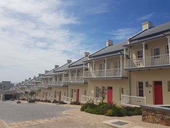 Residential buildings by street against sky