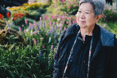 Senior woman looking away while standing at park