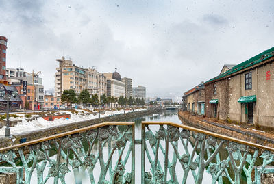 Canal amidst buildings in city against sky during winter