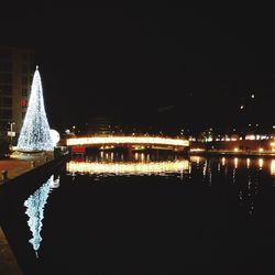 Illuminated bridge over river against sky at night