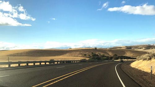 Empty road along landscape against sky