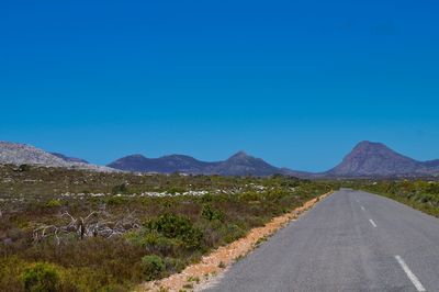 Road by mountains against clear blue sky