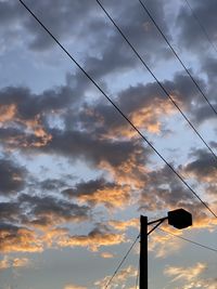 Low angle view of silhouette power lines against dramatic sky