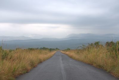 Road amidst green landscape against sky