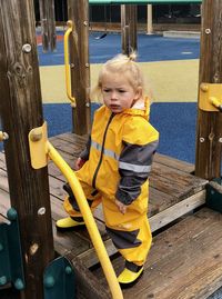 Full length of boy wearing raincoat while standing in playground