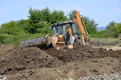 Construction site by road on field against sky