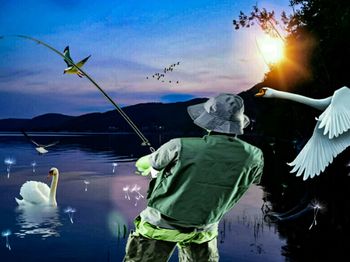 Rear view of man flying by lake against sky