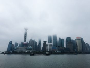 City at waterfront against cloudy sky