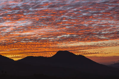 Scenic view of silhouette mountain against orange sky