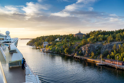 Scenic view of river by buildings against sky during sunset