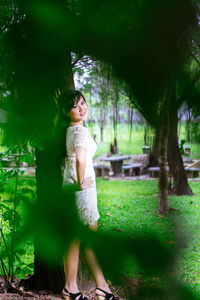 Side view of woman standing against trees