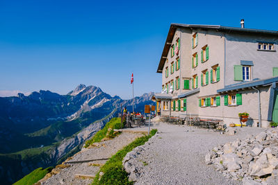 Road amidst buildings against clear blue sky