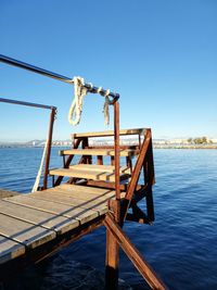 Pier over sea against clear blue sky