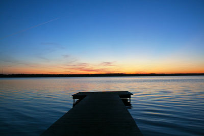 Pier on lake against sky during sunset