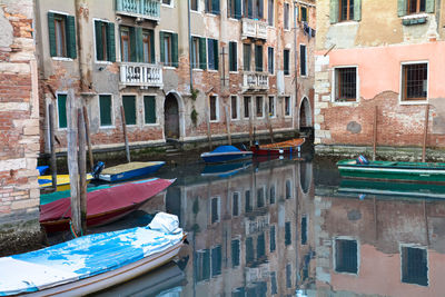 Boats moored in canal against buildings in city