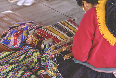 Indigenous woman showing traditional weaving technique and textile making in the andes 