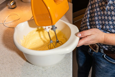 Midsection of woman preparing food in bowl on table