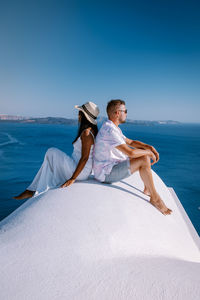 Full length of woman sitting on beach against blue sky