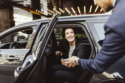 Smiling female entrepreneur looking at male coworker while sitting in car