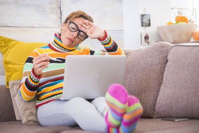 Midsection of man using mobile phone while sitting on sofa at home