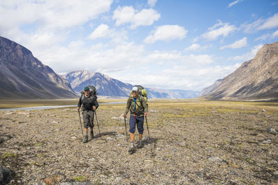 Rear view of men walking on mountain against sky