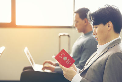 Side view of woman using digital tablet while sitting in cafe