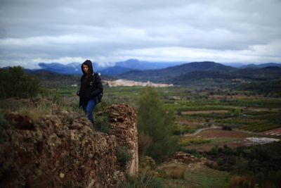 Man standing on field against cloudy sky