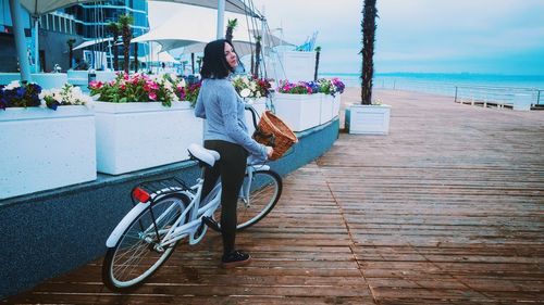 Woman with bicycle looking away while standing on promenade