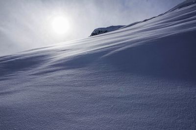 Low angle view of sun shining through clouds