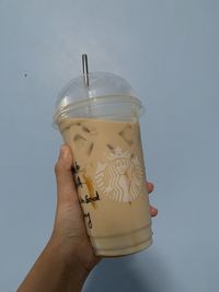 Close-up of hand holding drink against glass