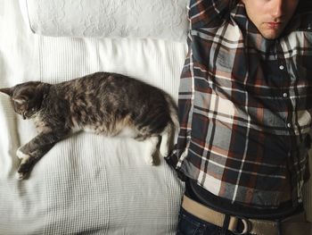 Midsection of man sleeping by cat on bed at home