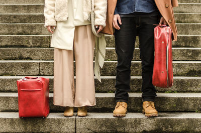 Low section of couple with luggage standing on steps